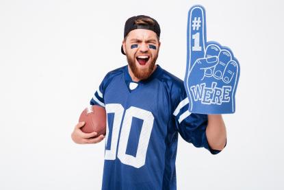 man in blue football jersey with blue foam pointing finger